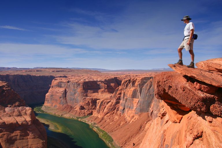 mann steht auf felsvorsprung mit ausblick auf grand canyon schlucht
