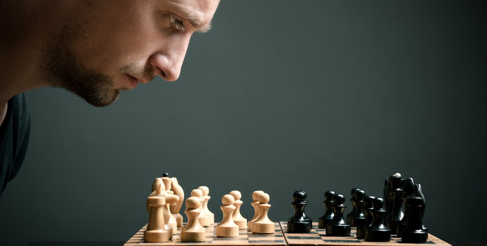 mann beim ueberlegen der schach-strategie mit schachbrett