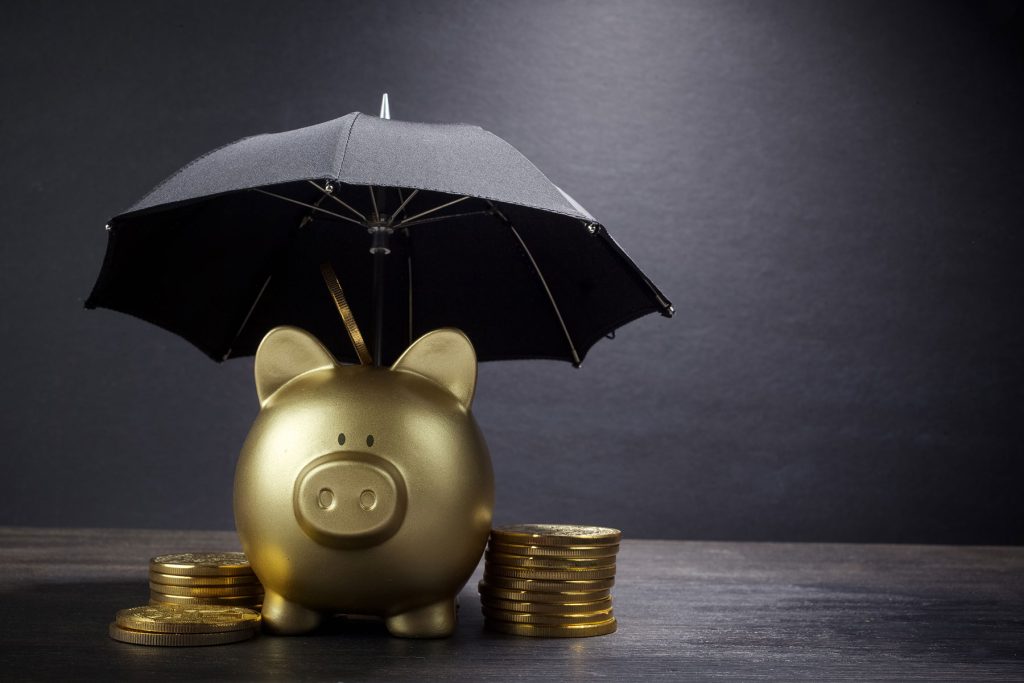 insolvenz-schutz dargestellt mit goldenem sparschwein und regenschirm darueber