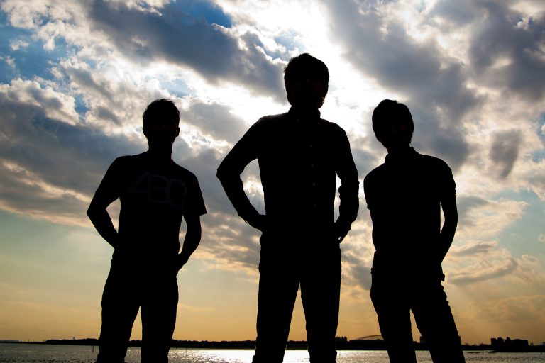 drei jung-unternehmer im schatten fotografiert mit sonne und wolken im hintergrund