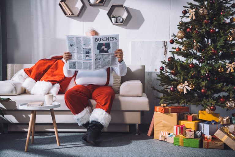 weihnachtsmann liest unternehmer-zeitung neben weihnachtsbaum