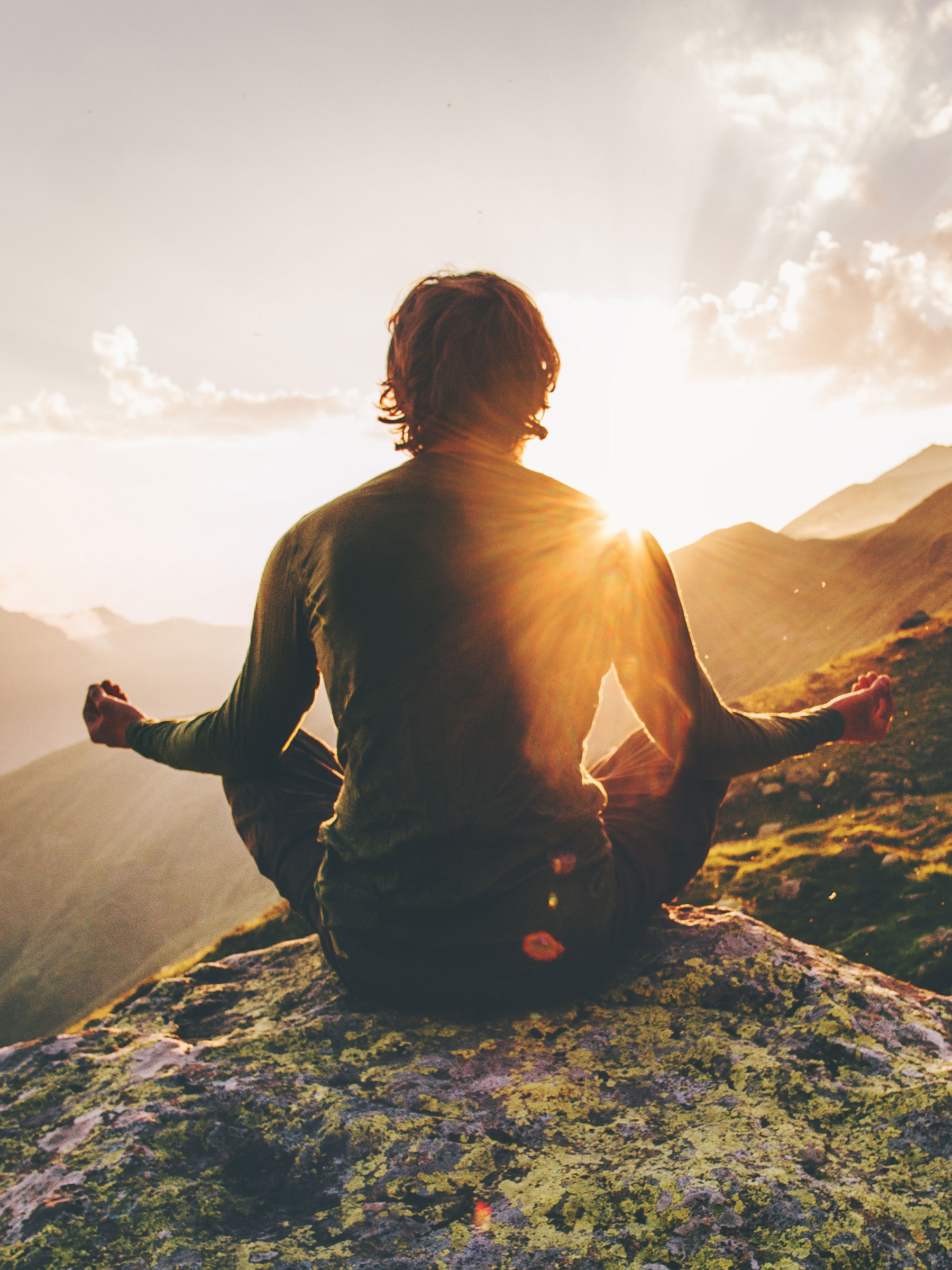 mann bei meditation bei sonnenaufgang in den bergen
