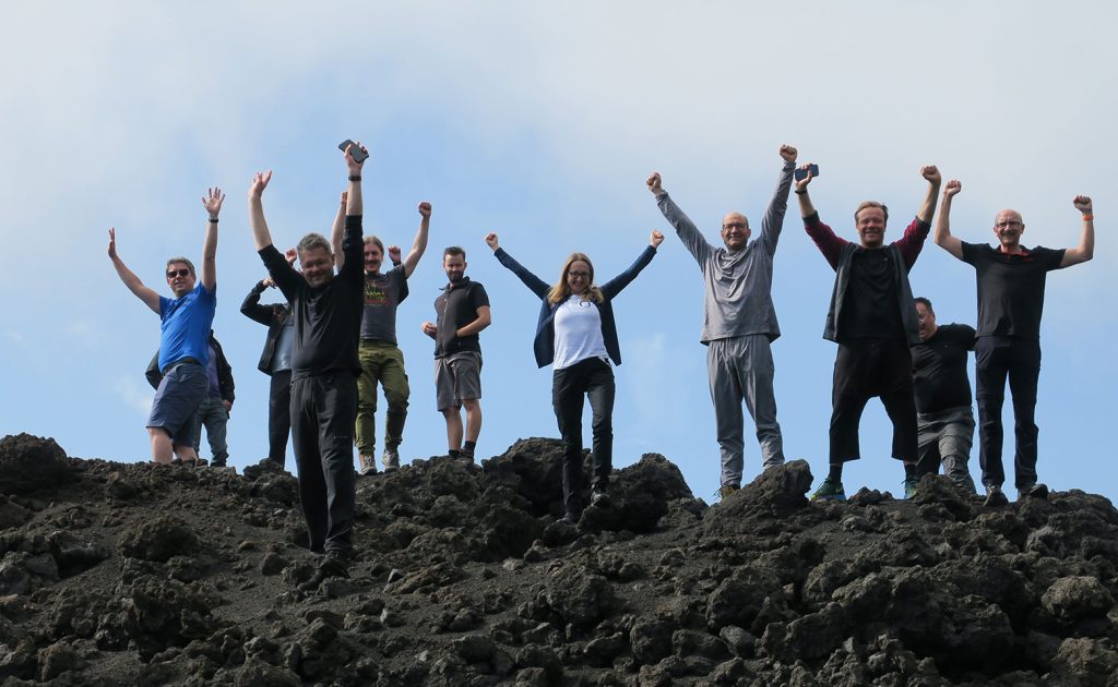 gruppen-foto von unternehmern mit haende nach oben auf vulakn-gestein auf sizilien