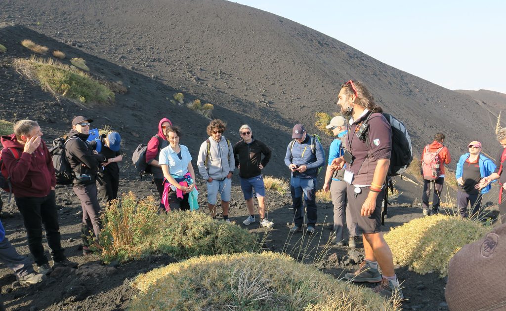 unternehmer-gruppe beim wandern auf sizilien beim vulkan mit tour-guide