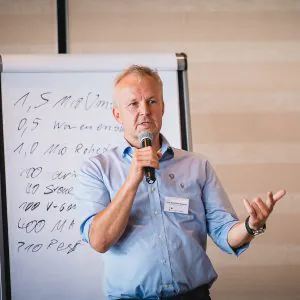 unternehmer joerg burkhard wagner mit mikrofon beim vortrag auf seminar