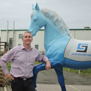Unternehmercoach Jens Schliessmeyer lehnt an der Pferdestatur seines Unternehmens