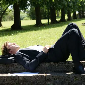 geschaefts-mann sonnt sich auf stein-treppe im park und fuehlt sich frei